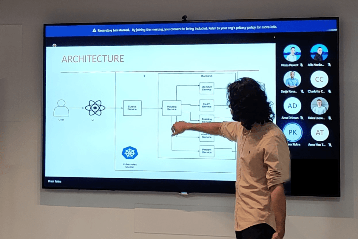 Stagiair verteld aan de hand van een presentatie de schematische voorstelling van een microservice IT-architectuur